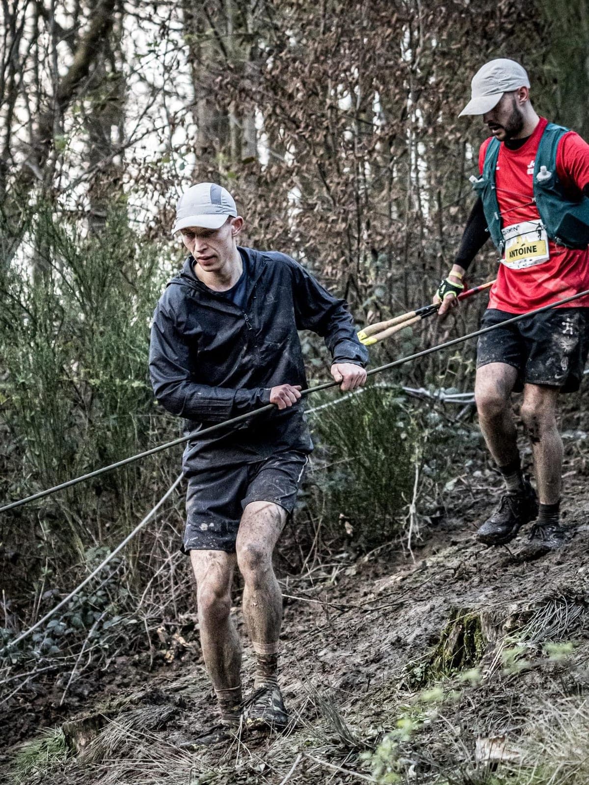 Dans une descente boueuse d'un Dernier Homme Debout, un coureur du clan se retient à la corde
