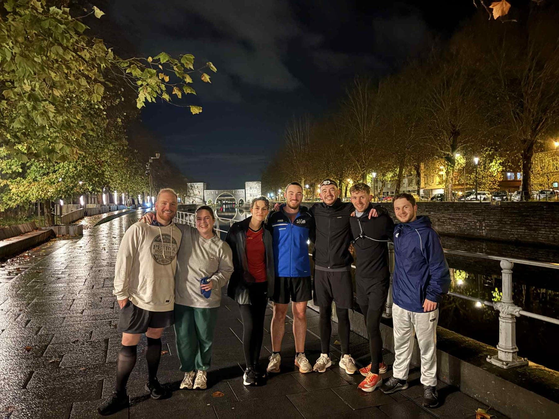 L'un des premiers V'Hiking Runs : huit coureurs posent de nuit sur le quai, le Pont des Trous derrière eux