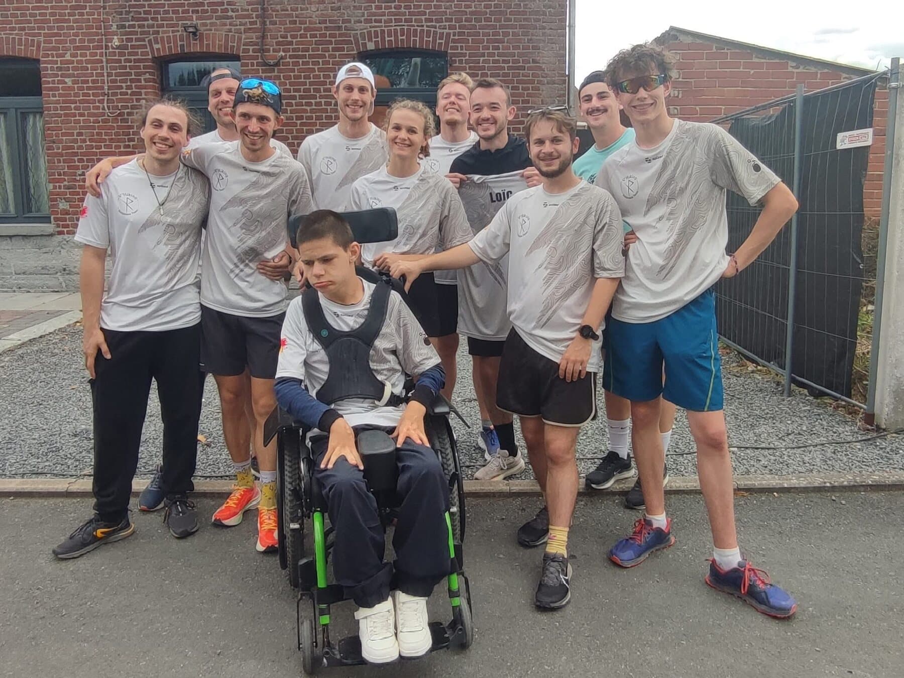 L'équipe du relais de 2025 pose autour d'Éloi, dans son fauteuil, tout le monde en t-shirt gris à la rune