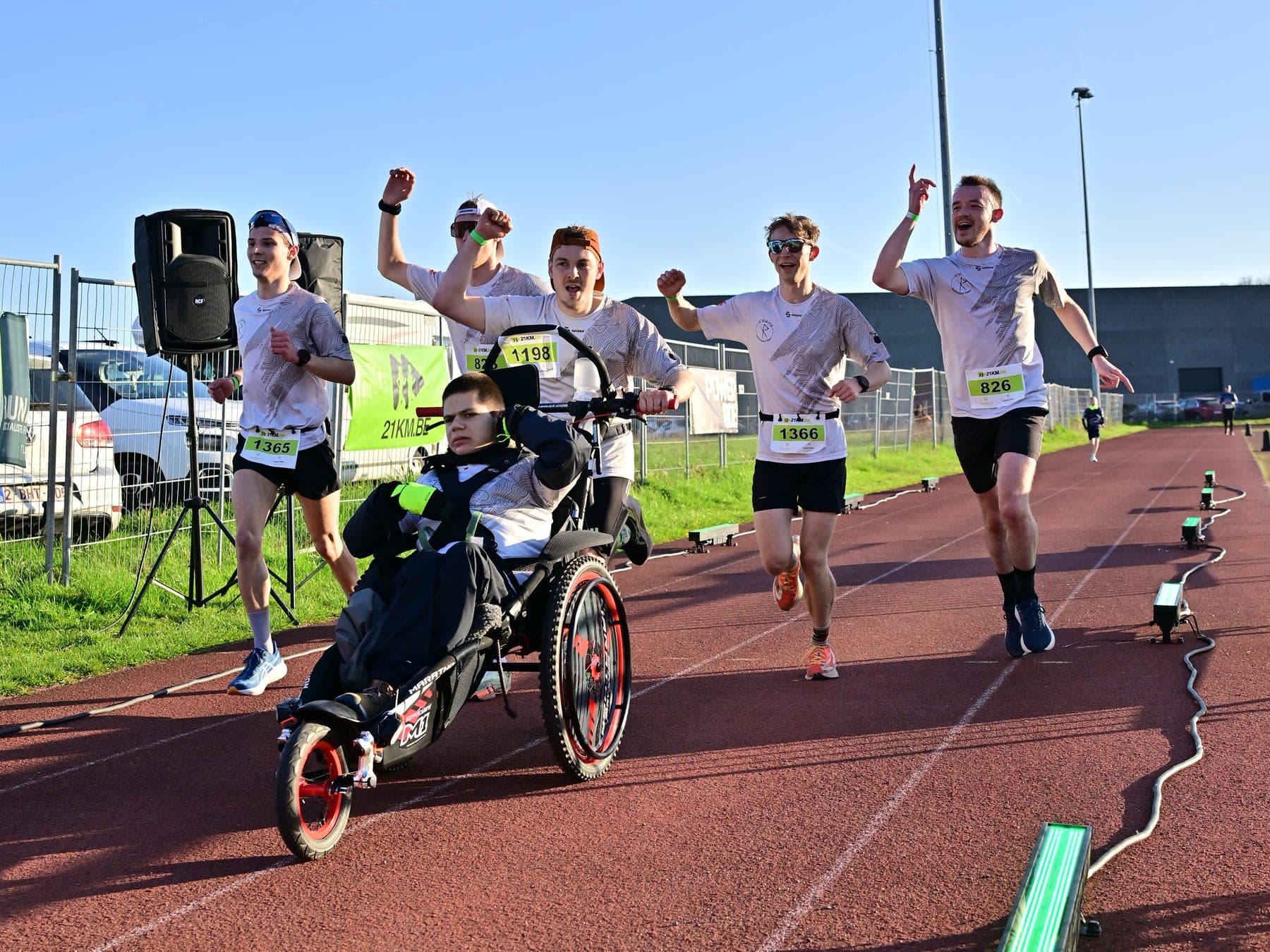 Des V'Hikings bras levés et la joëlette sur la piste d'athlétisme du semi-marathon de Dour