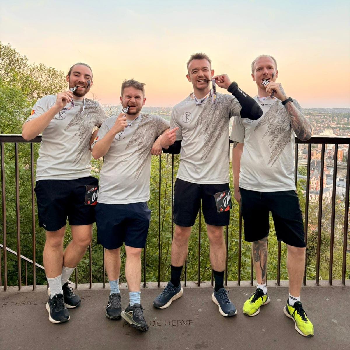 Quatre V'Hikings croquent leur médaille de la Buerun, au coucher du soleil sur Liège