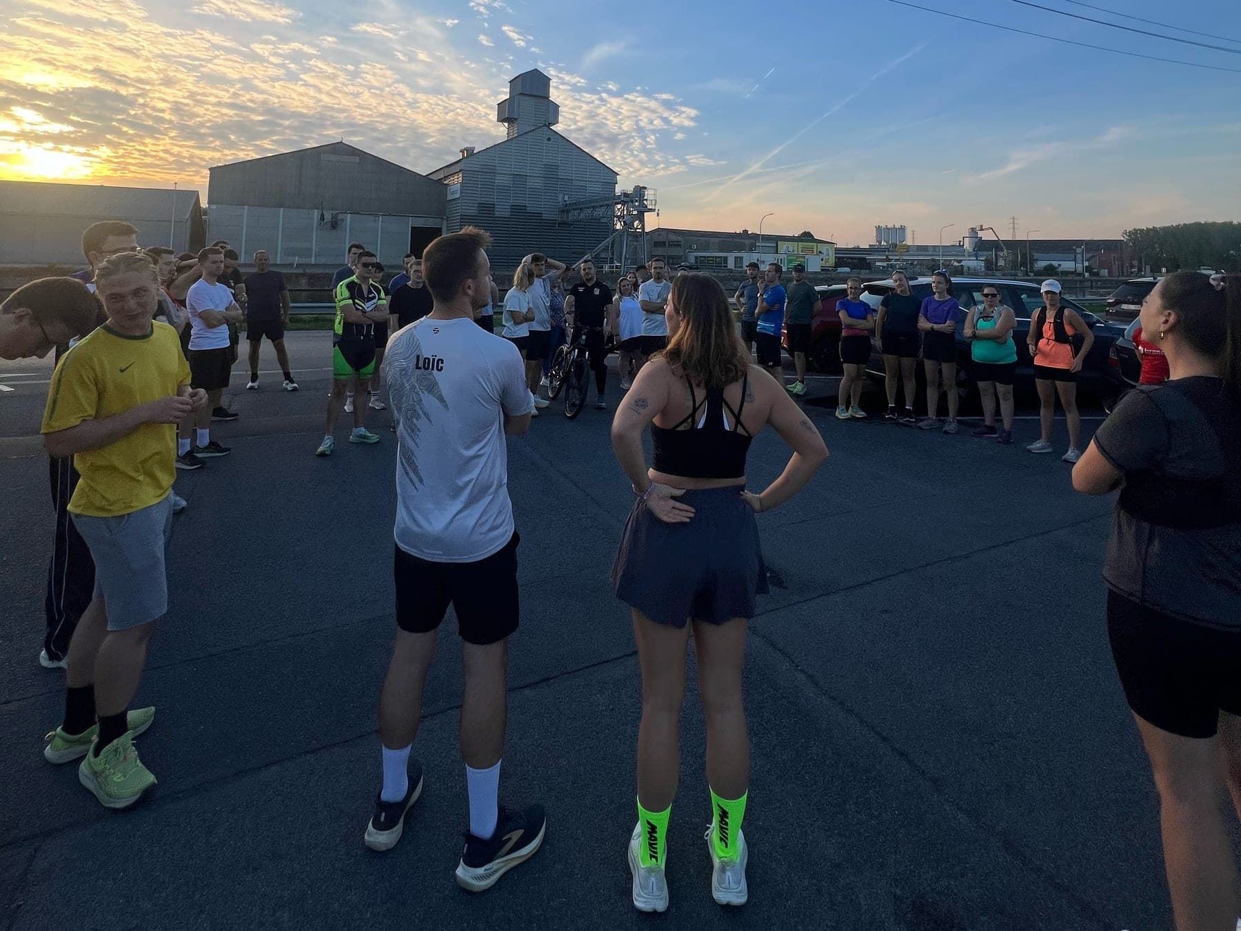 Le clan en cercle sur le parking de Sports Rive Droite au coucher du soleil, juste avant le départ